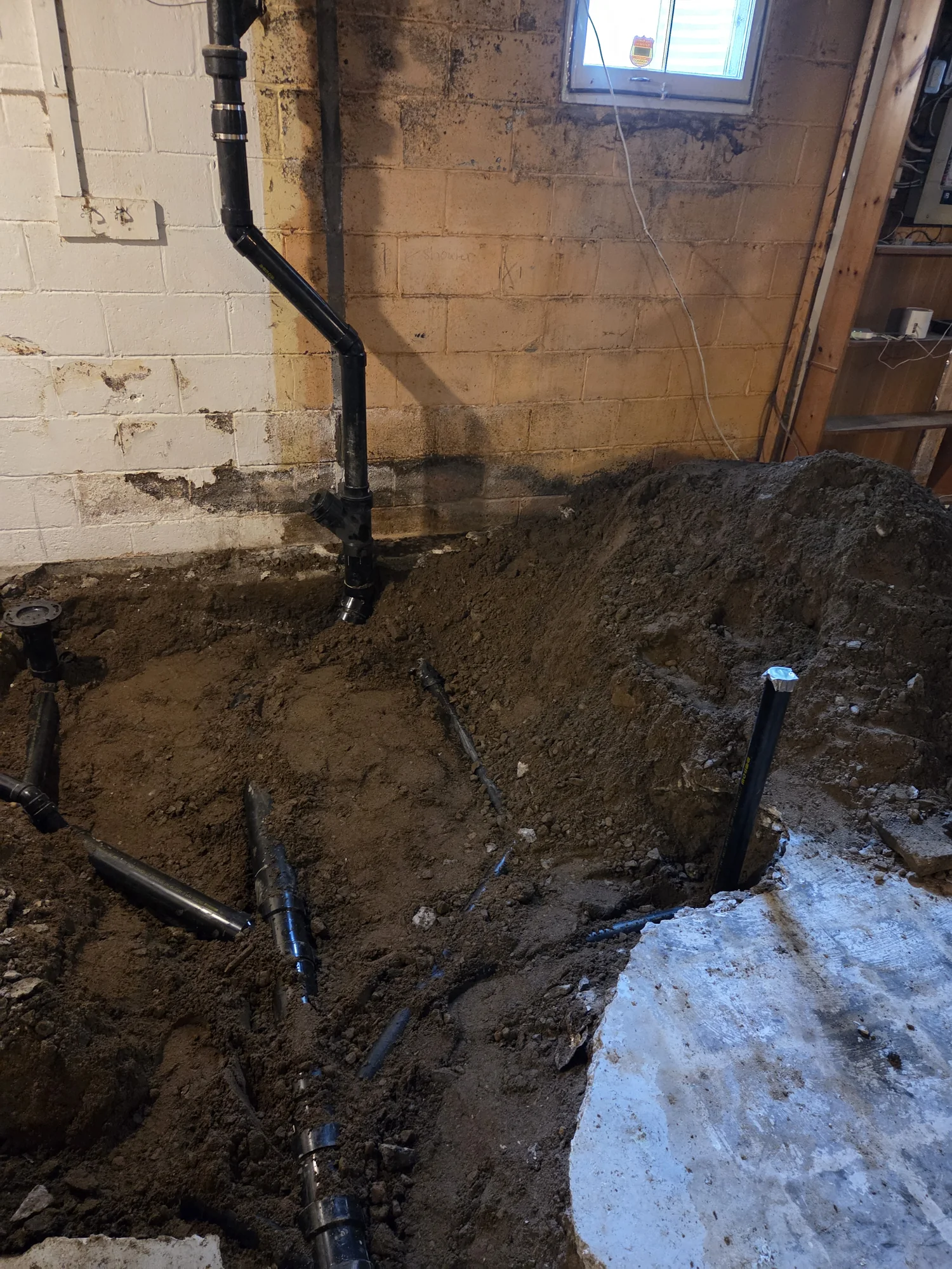 Basement sewer replacement trench with exposed drain piping