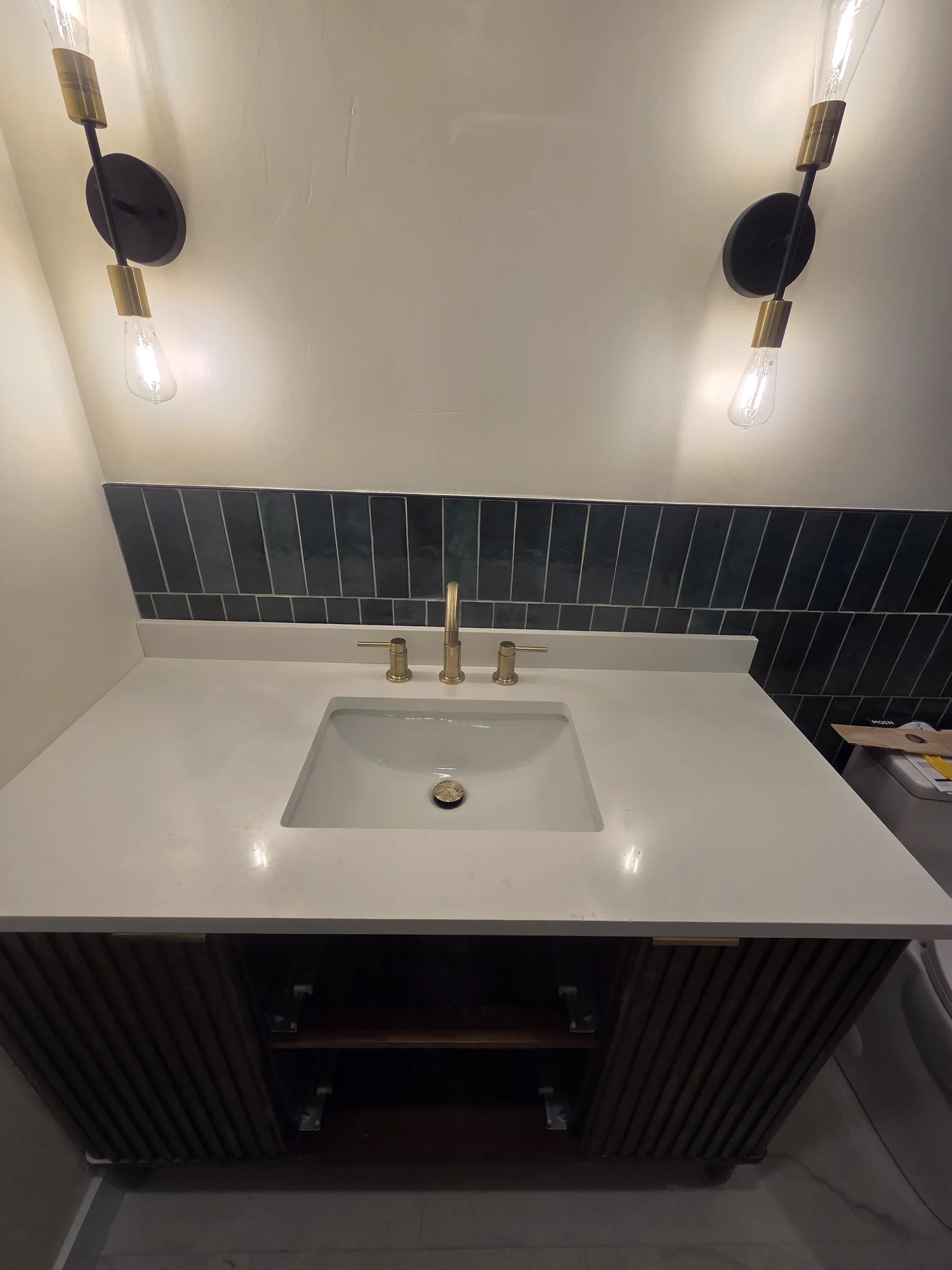 Bathroom vanity with a brass faucet and wall lights
