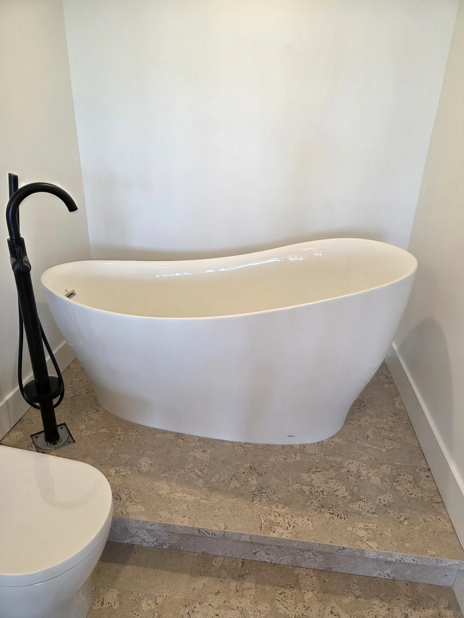 White freestanding bathtub with a black floor-mounted faucet