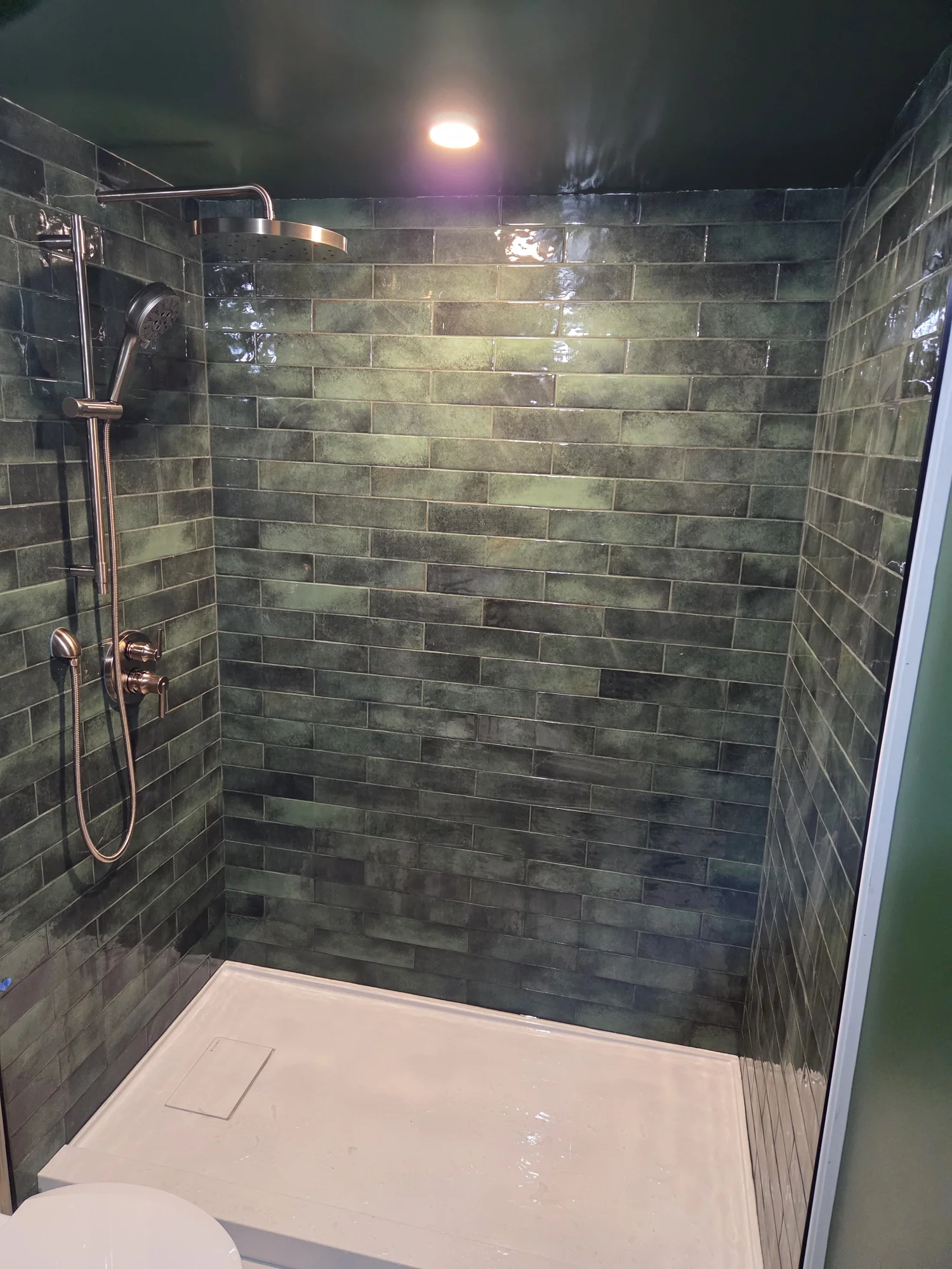 Glass shower enclosure with dark stone-look tiles