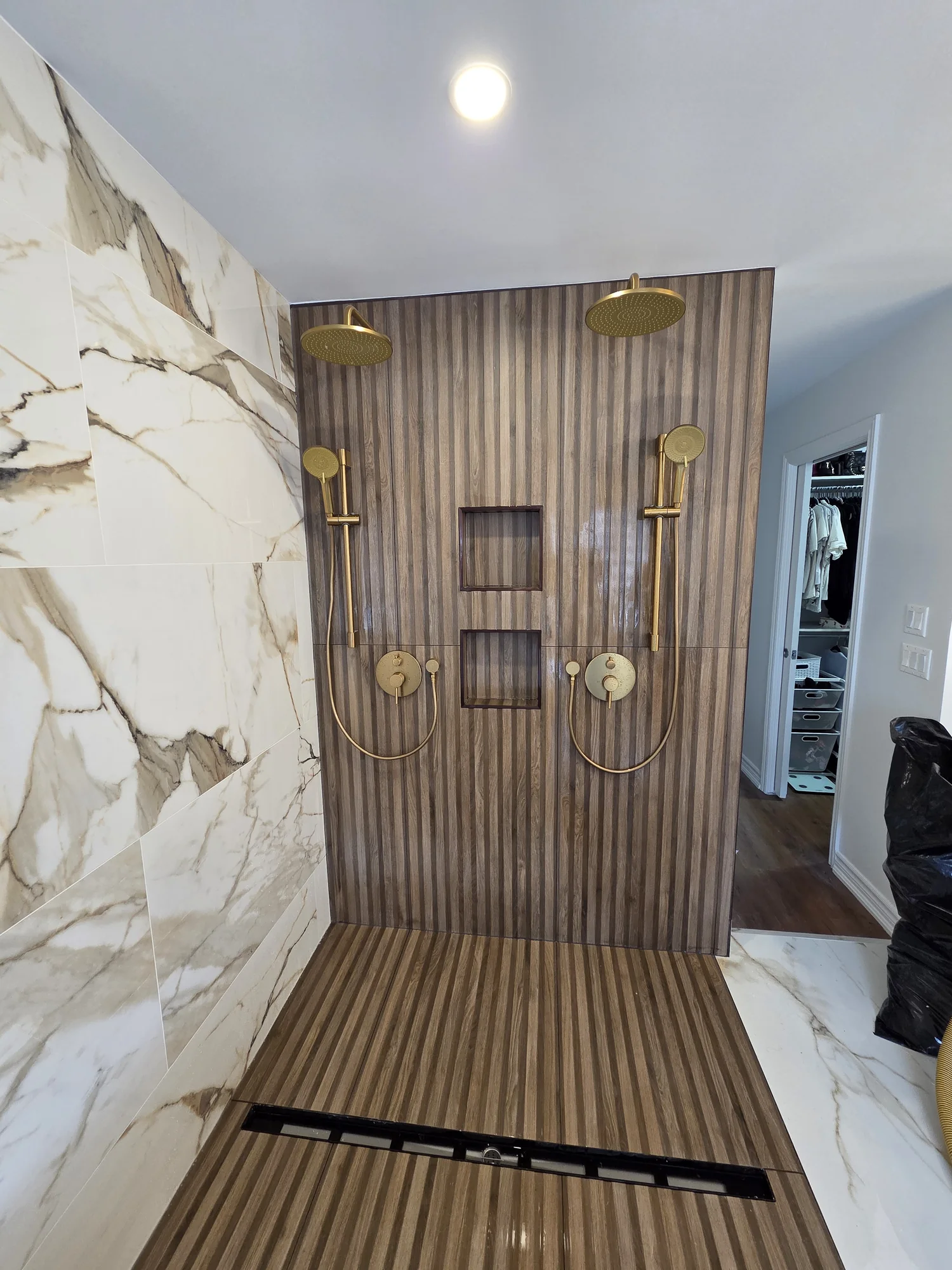 Walk-in shower with marble-effect walls and wood-look tile