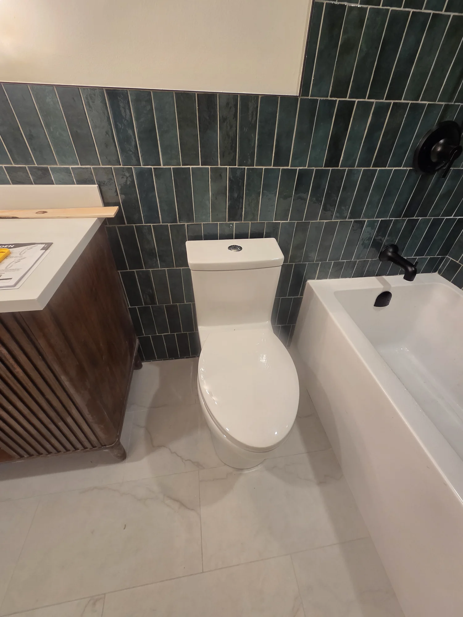 One-piece toilet between a vanity and bathtub