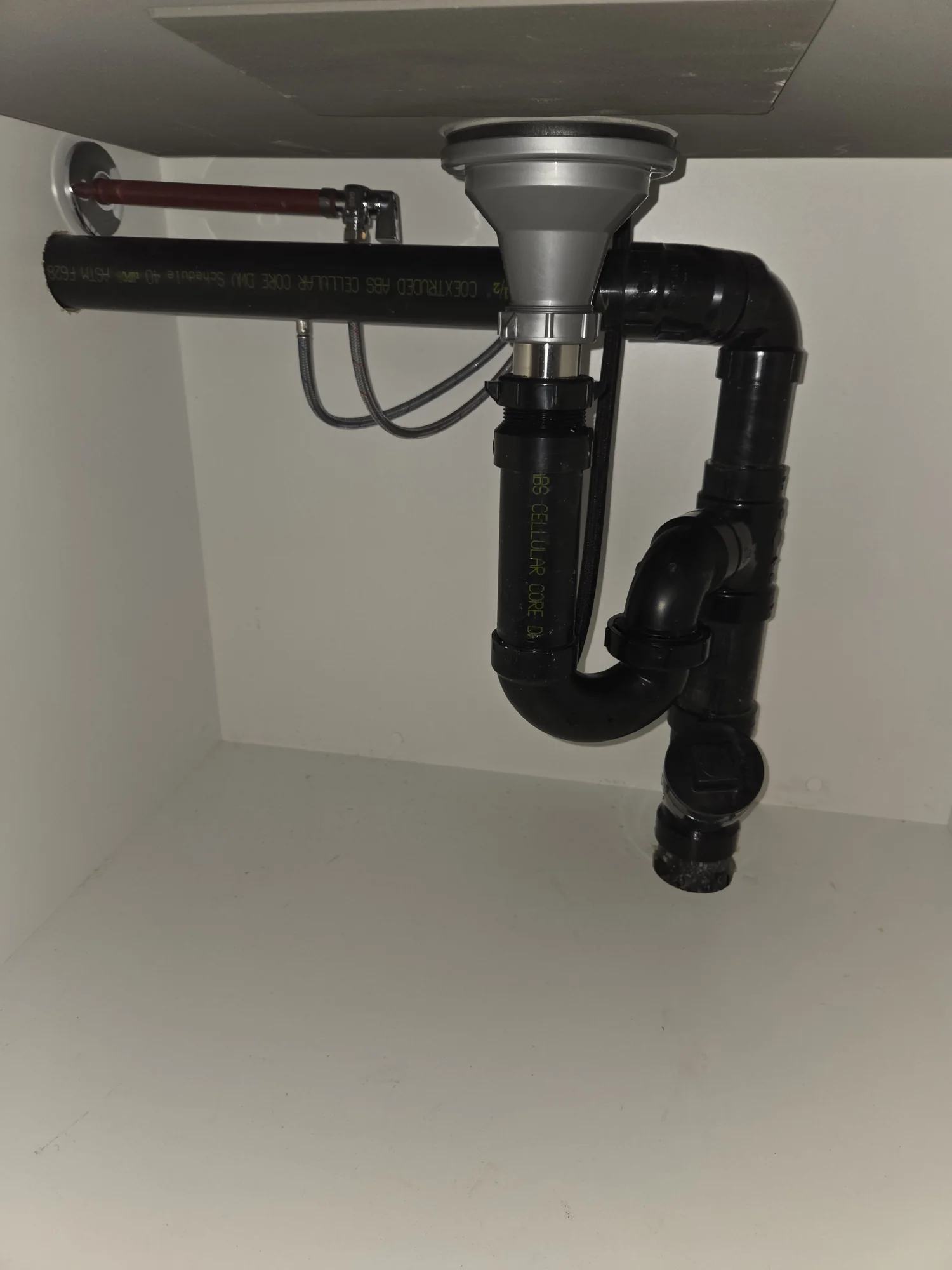 Black ABS drain trap beneath a single sink