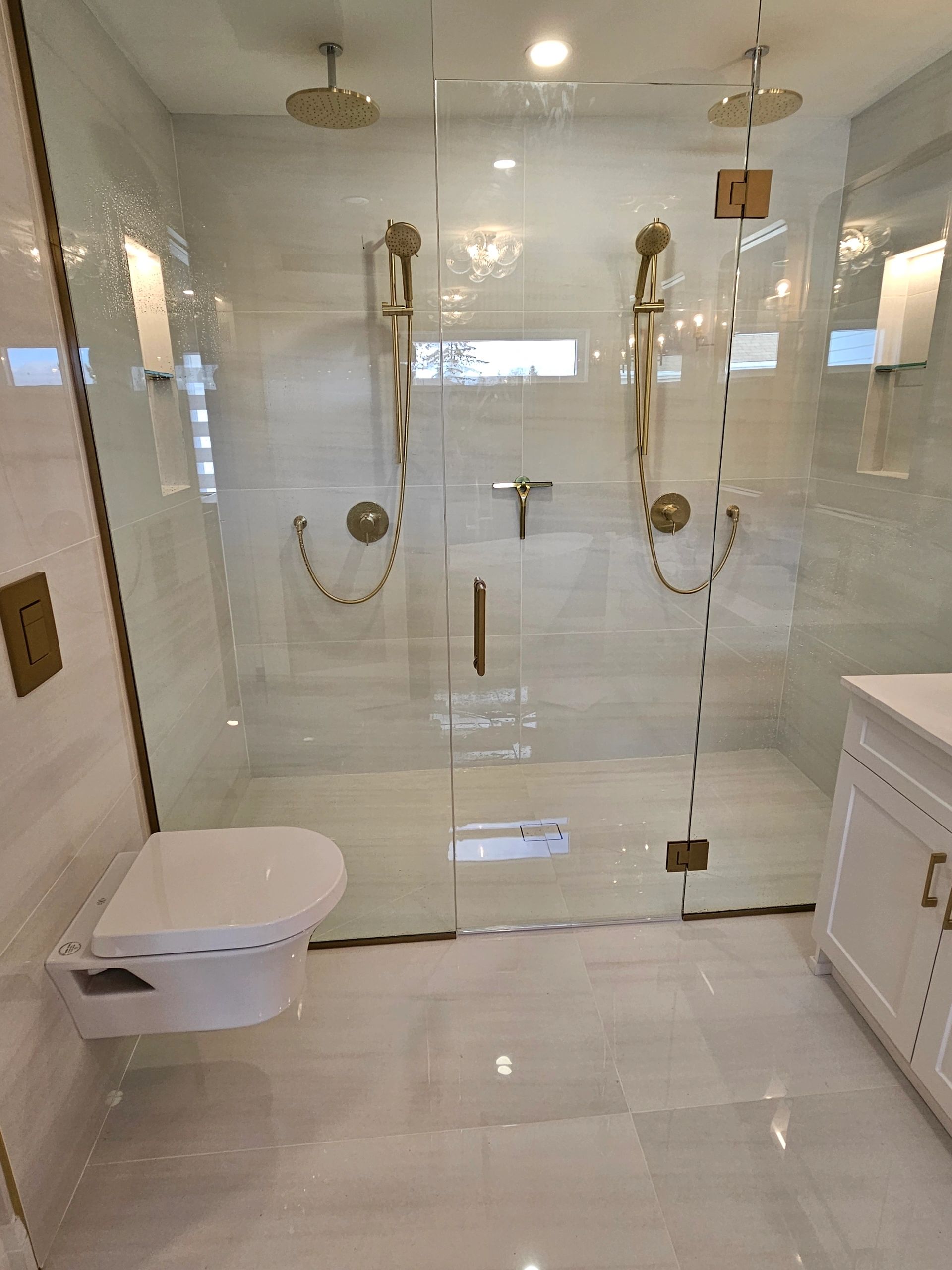 Finished bathroom with glass shower, toilet and vanity by Hydra Plumbing